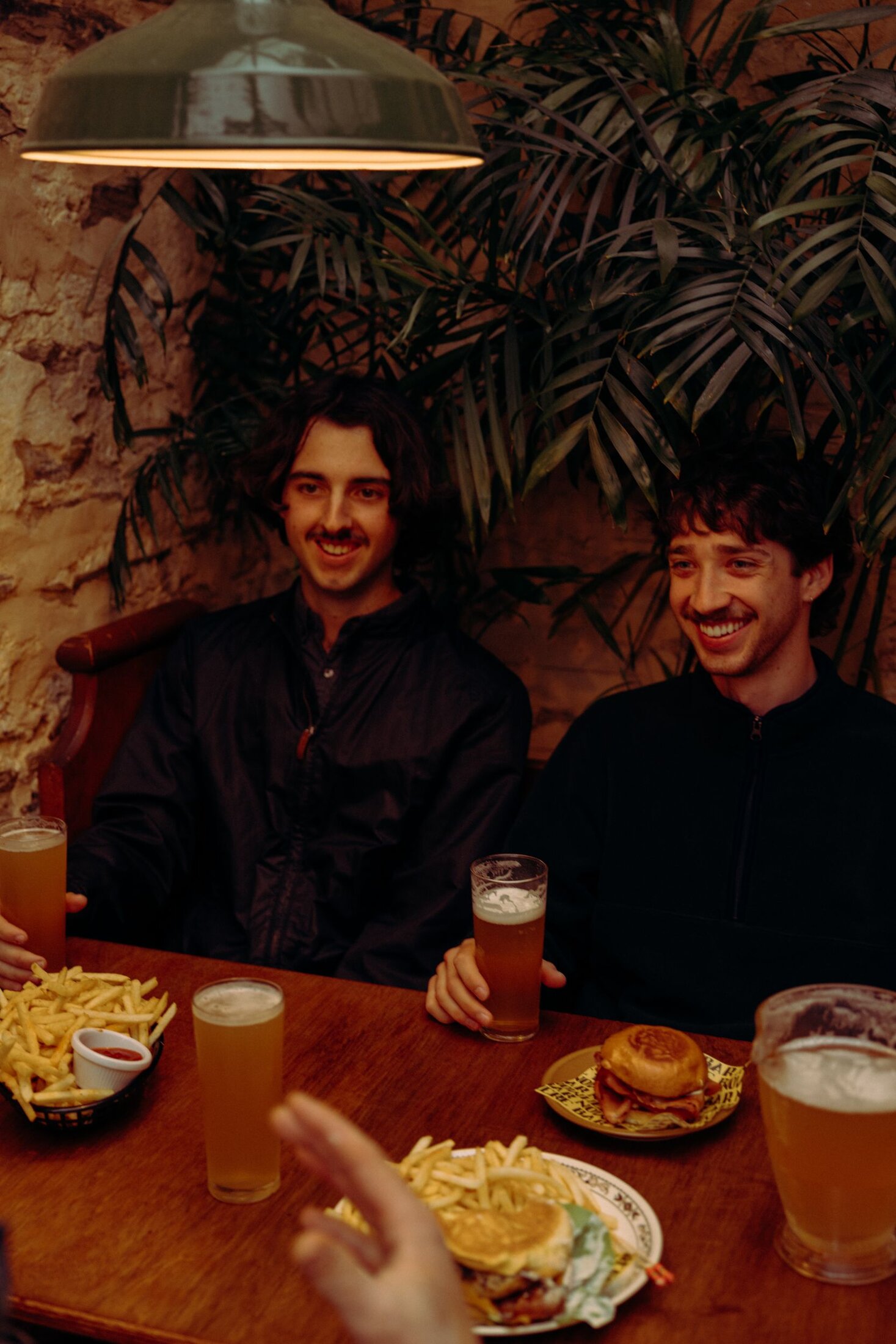 Friends gathered at a table inside Nowhere Bar, under the palms and warm light